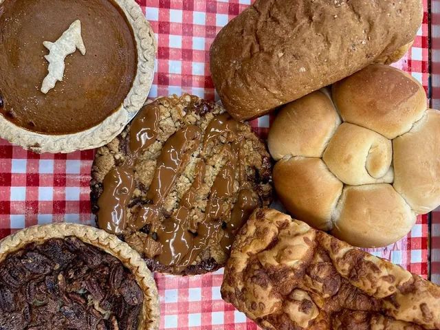 A variety of breads and pastries are sitting on a checkered table cloth.