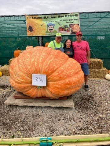 A group of people standing next to a large pumpkin.