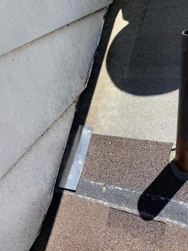 A person is standing on a sidewalk next to a house.