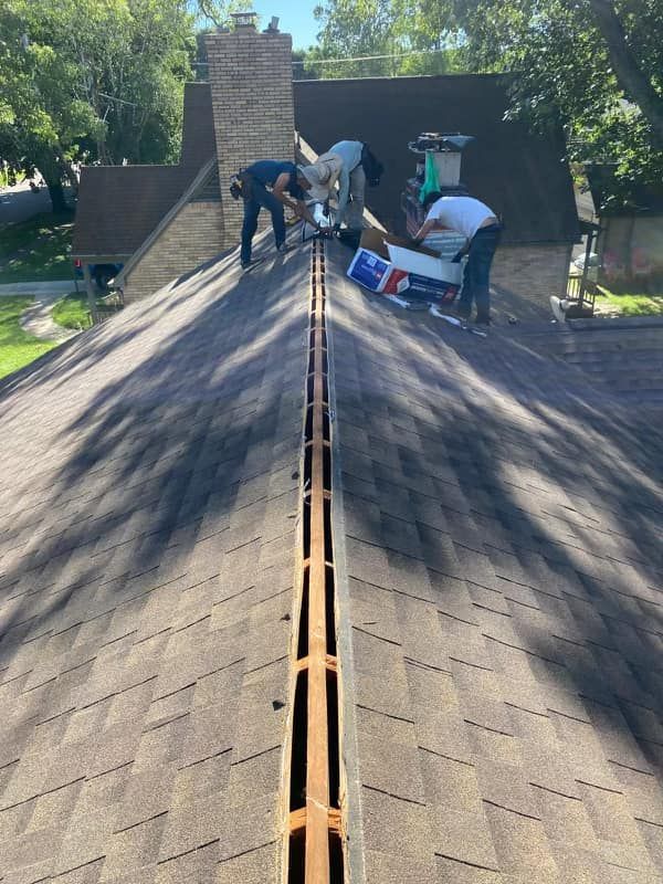 A group of men are working on the roof of a house.