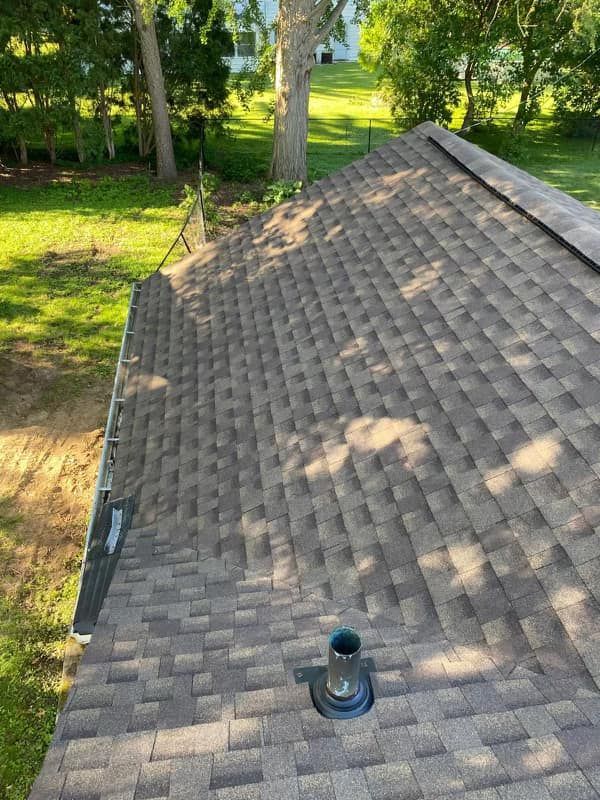 A roof with a chimney on it and a tree in the background.