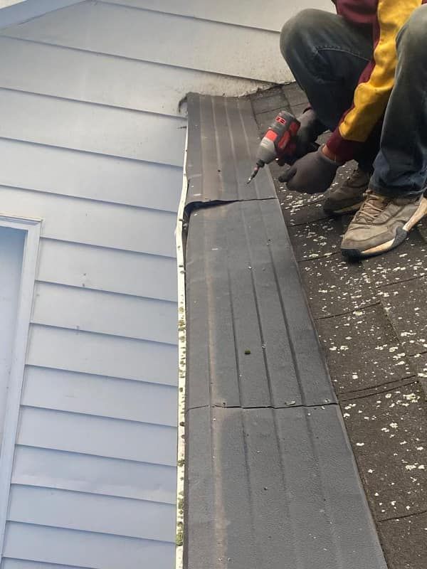 A man is working on a roof with a drill.