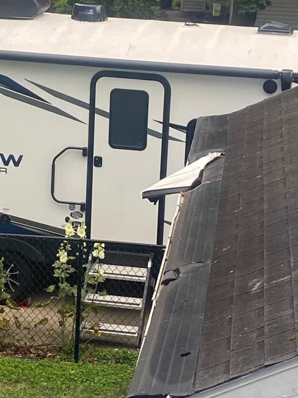 A white rv is parked next to a broken roof
