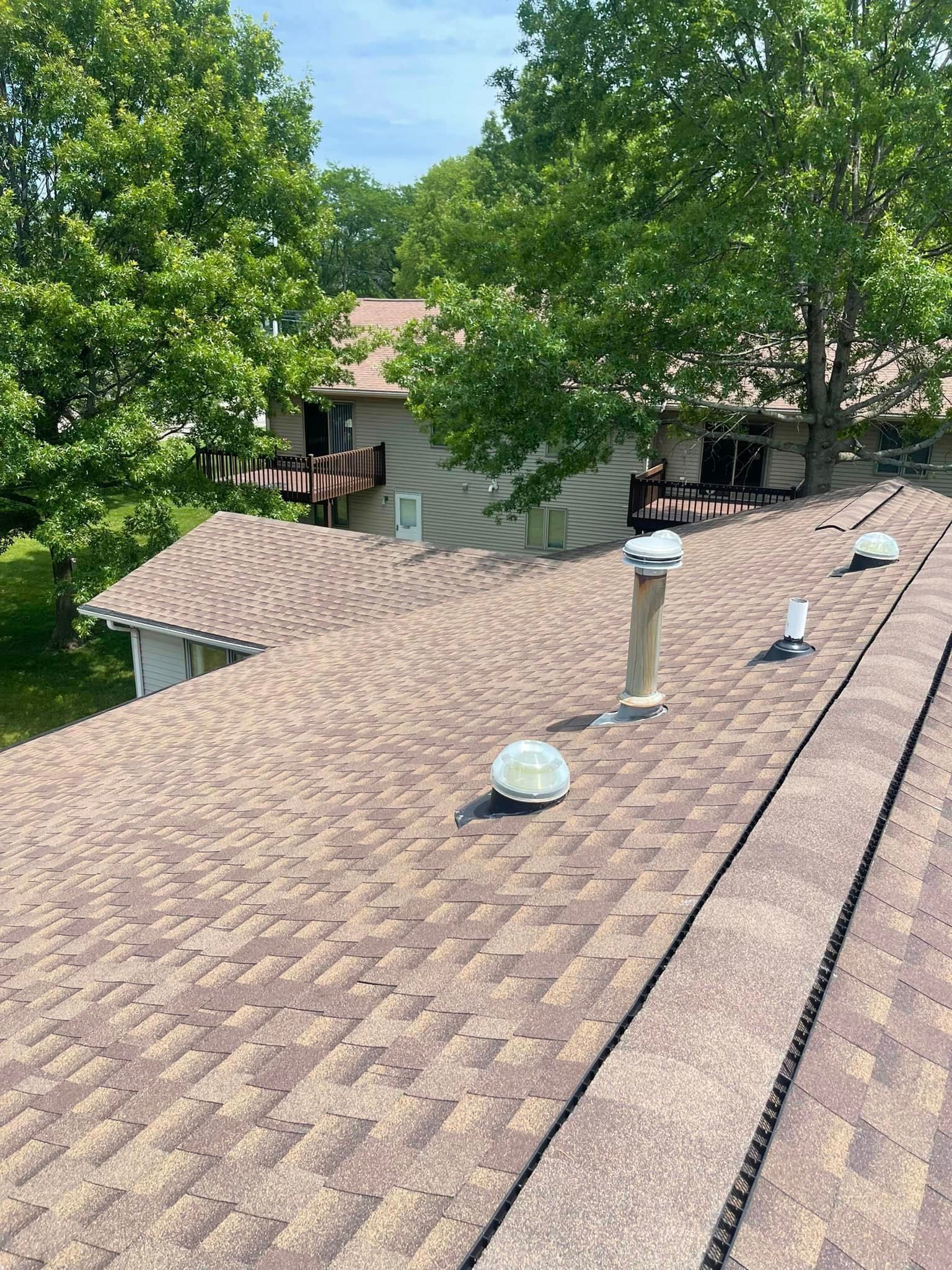 The roof of a house with a lot of trees in the background.