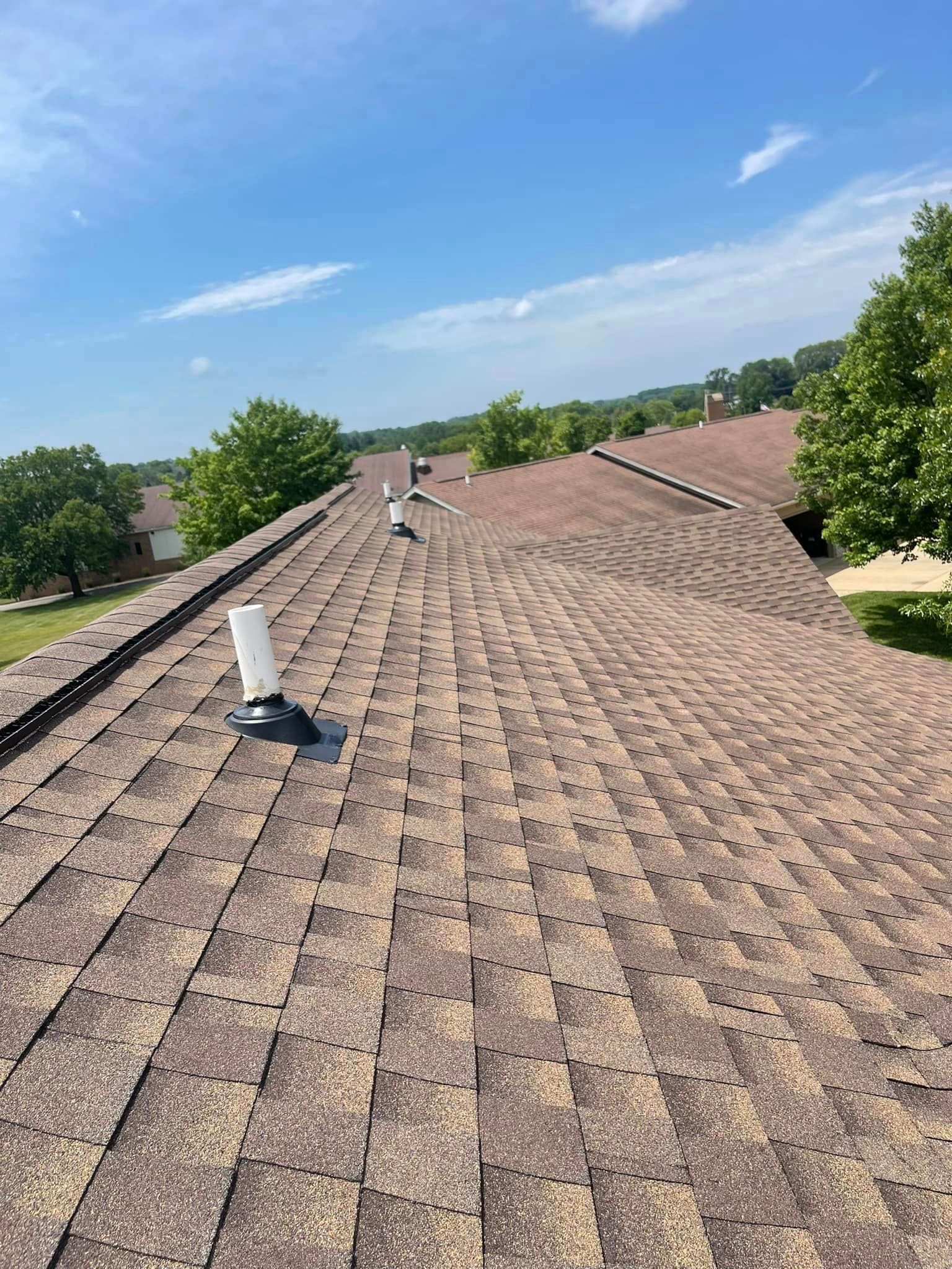 A roof with a skylight on it and trees in the background.