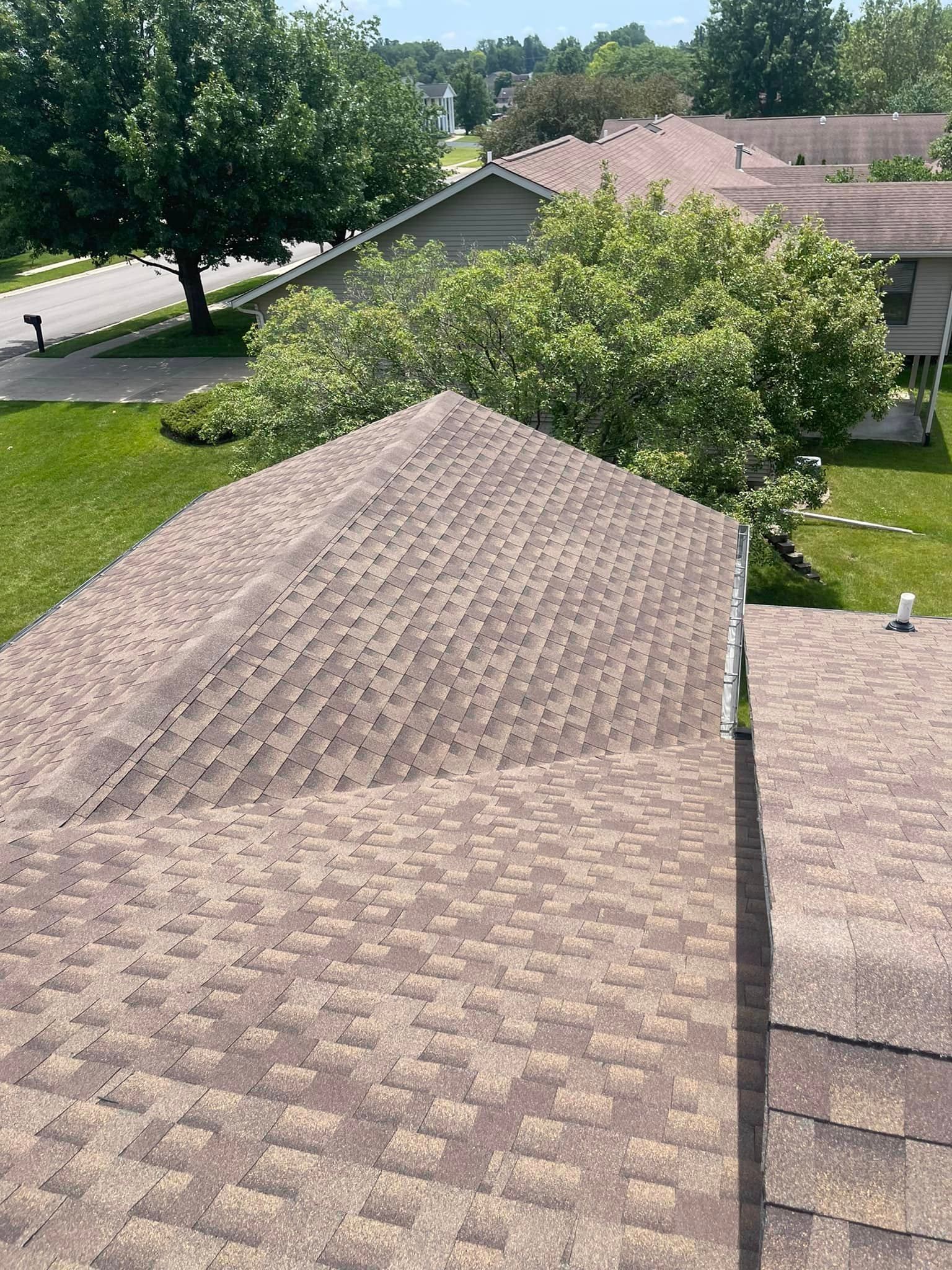 An aerial view of a roof of a house with trees in the background.