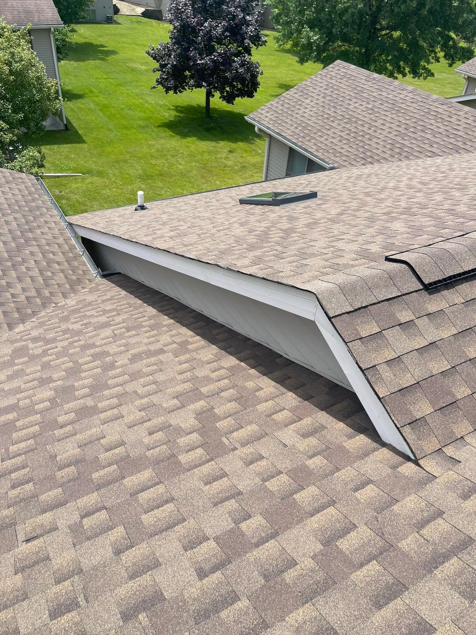 An aerial view of a roof of a house with a tree in the background.