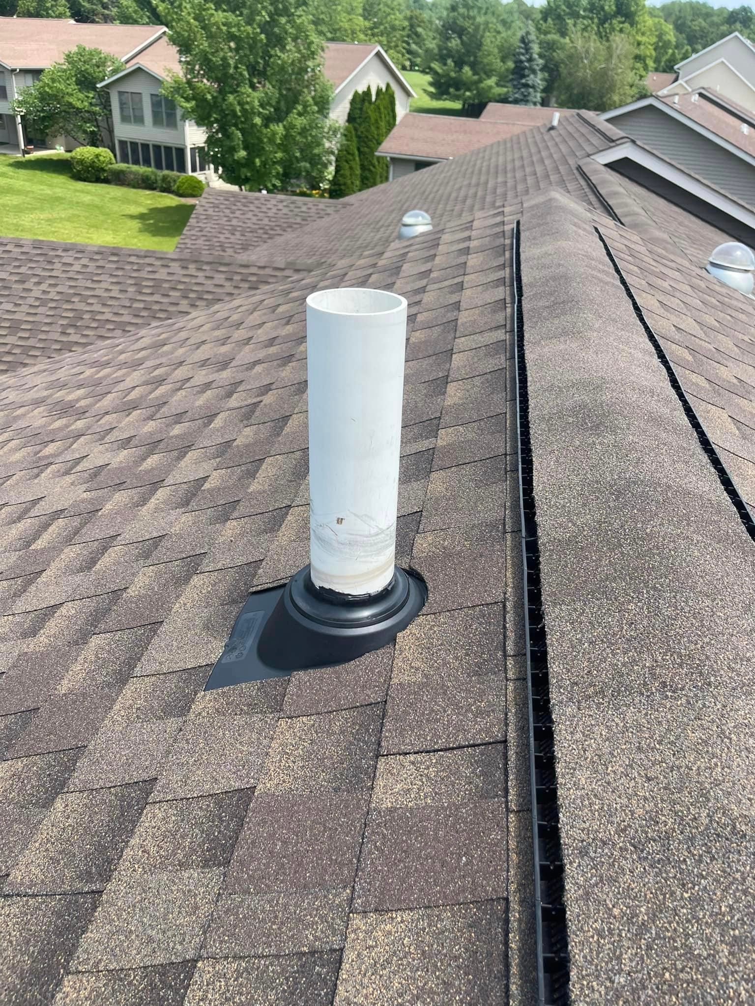 A white pipe is sitting on top of a roof.
