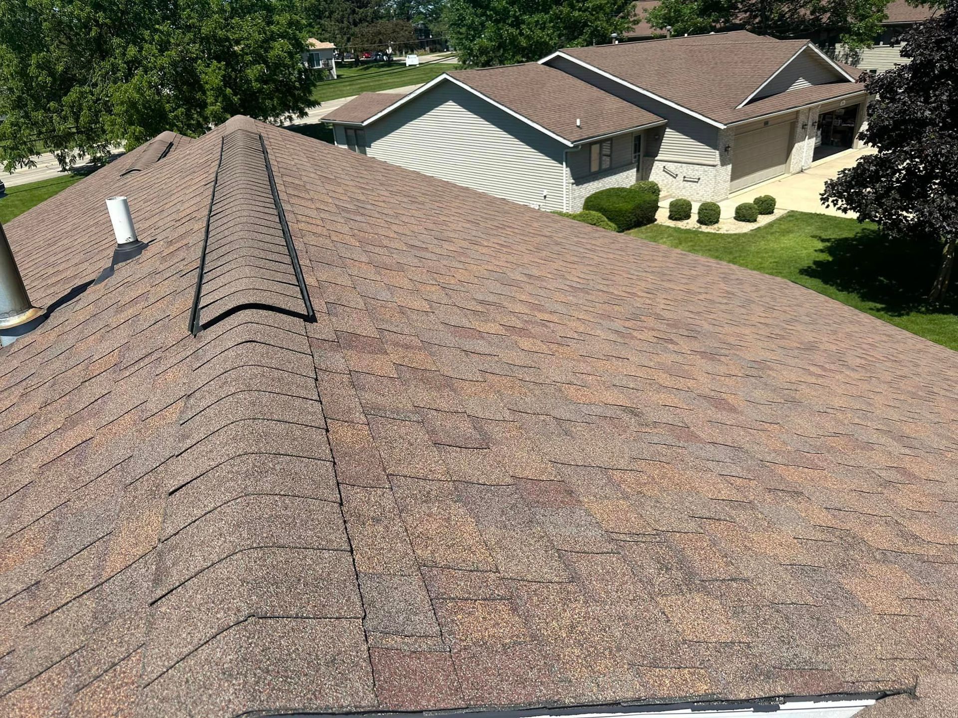 The roof of a house with a brown shingle roof.