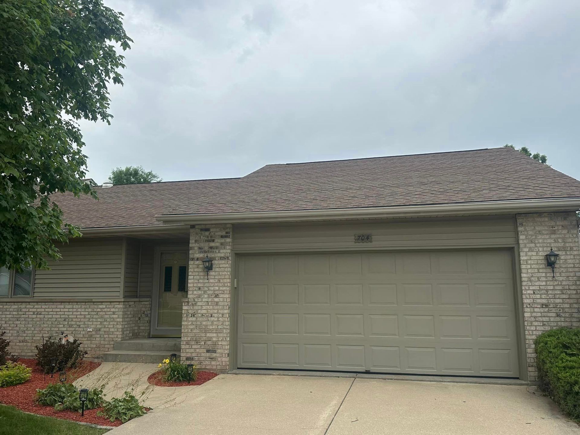 A house with a garage door and a brick wall