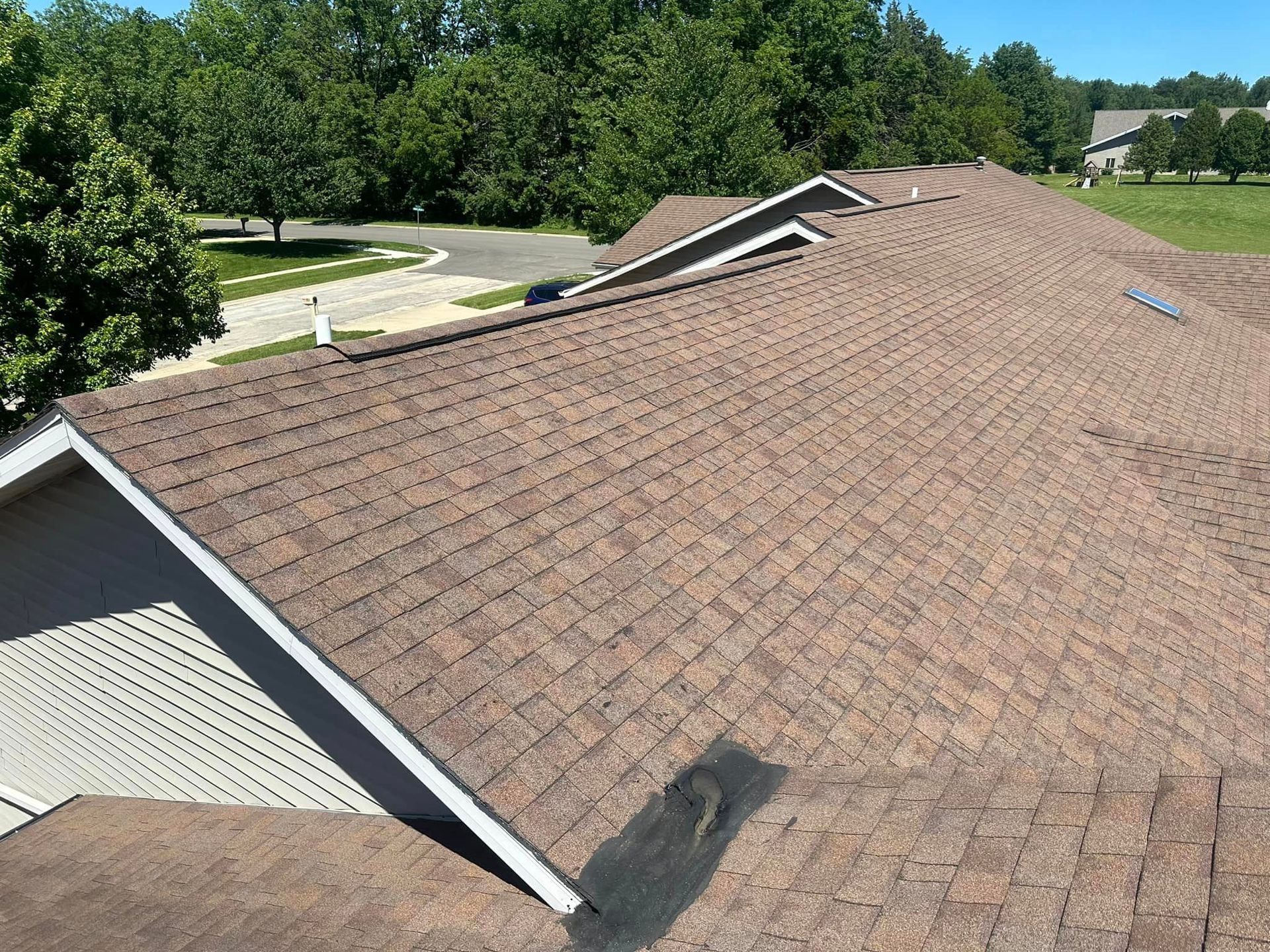 The roof of a house with a brown shingle roof.