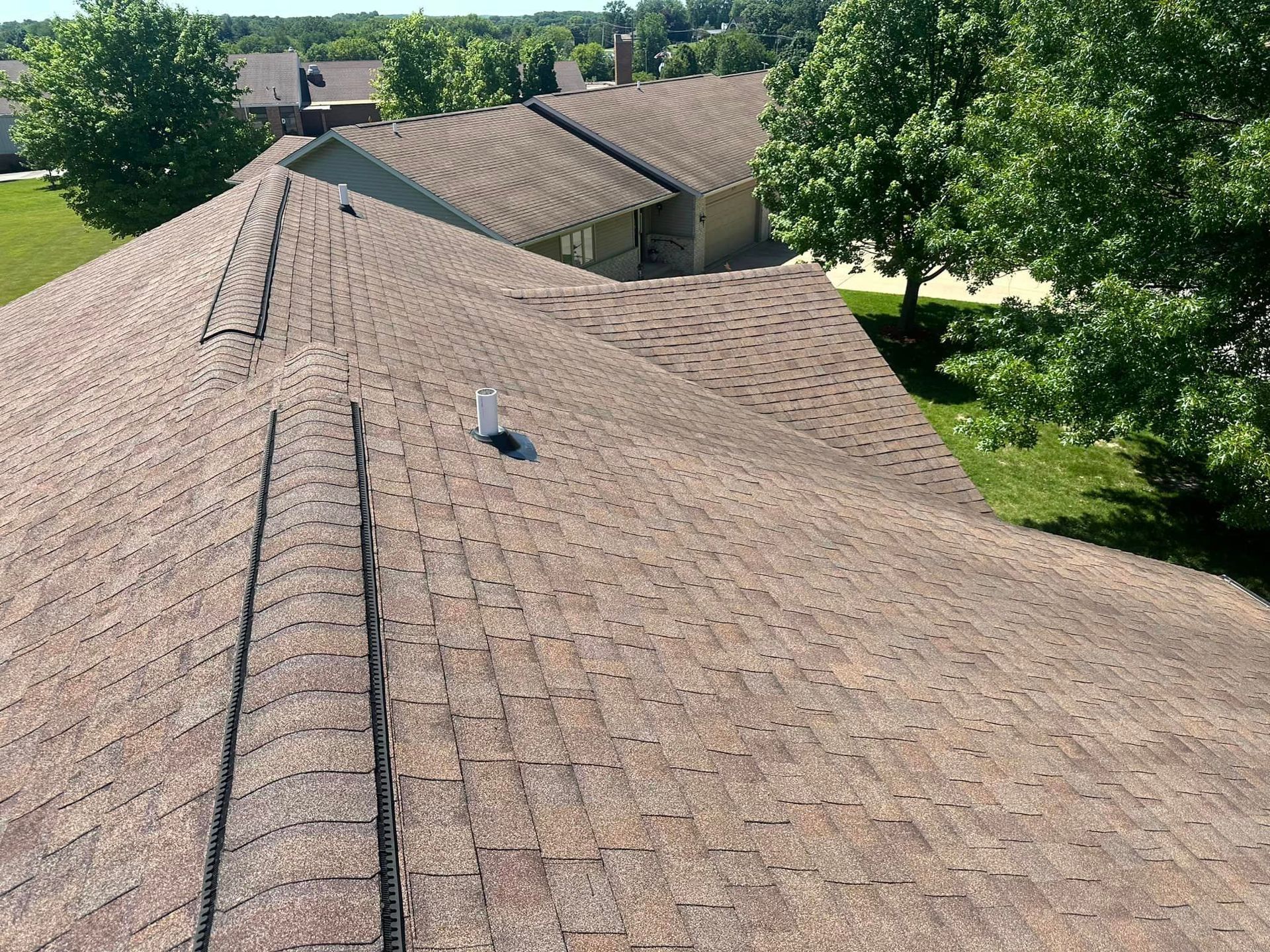 An aerial view of a roof of a house with trees in the background.