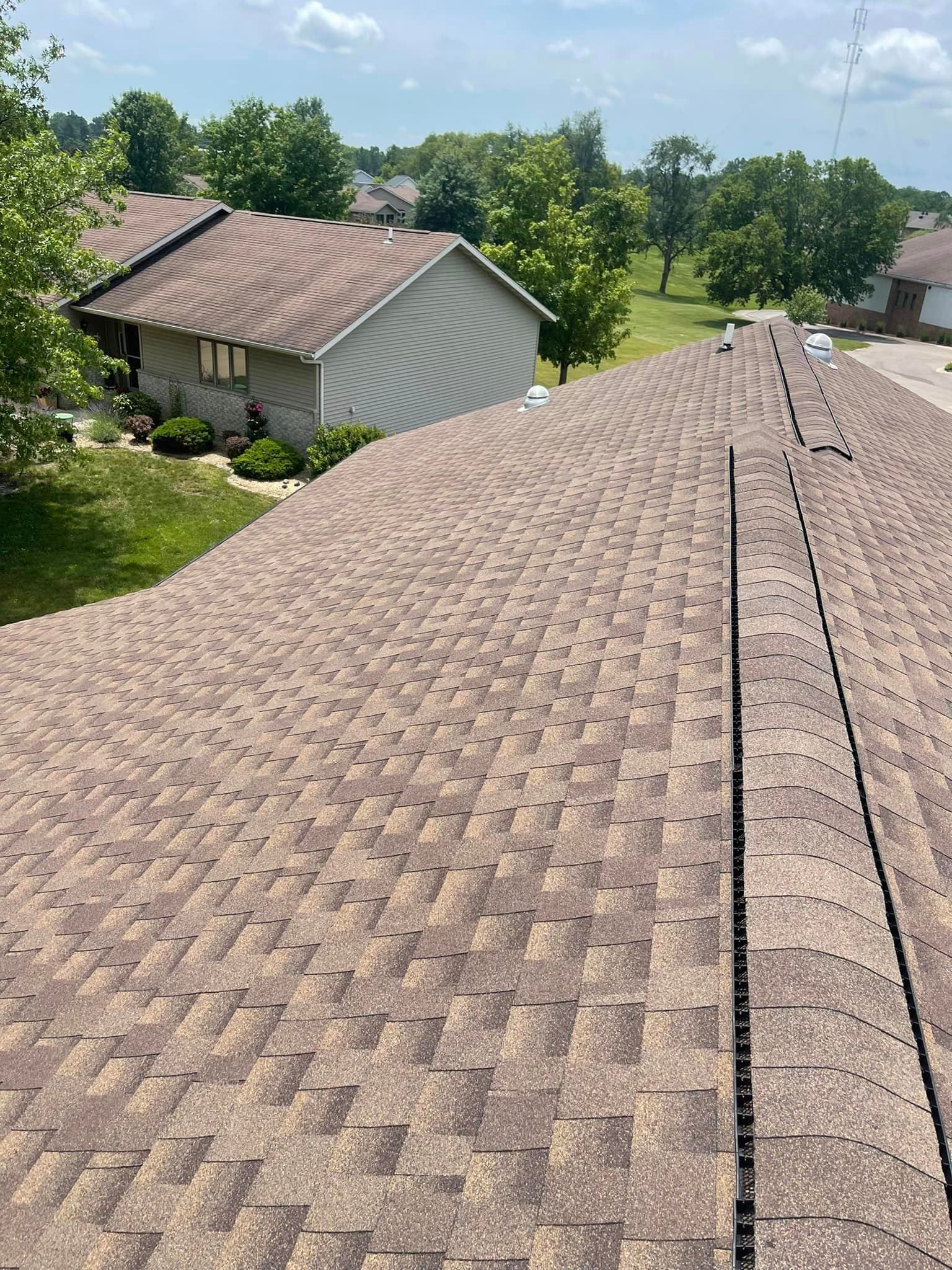 A roof with a lot of shingles on it and a house in the background.