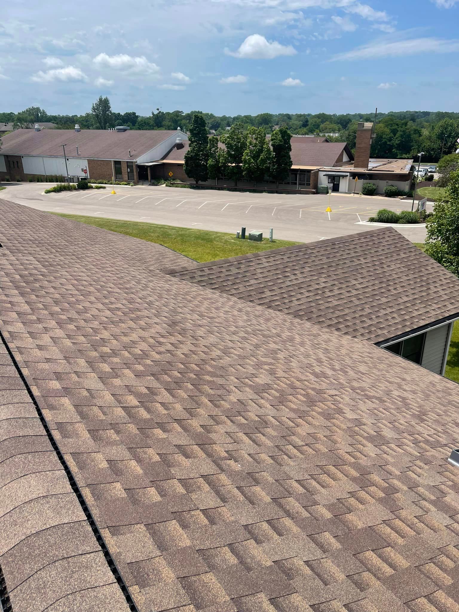 An aerial view of a roof of a house with a parking lot in the background.