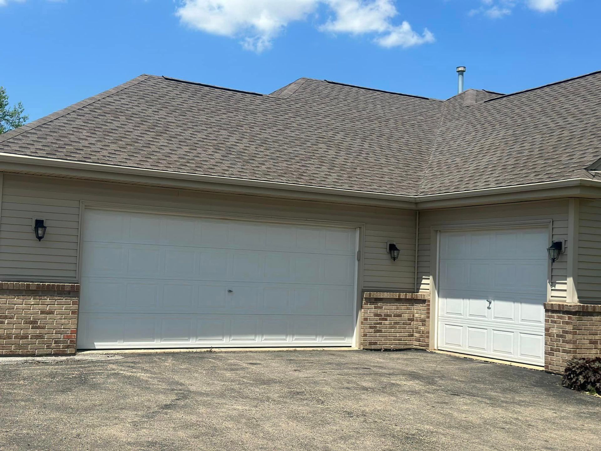 A house with two garage doors and a brown roof.