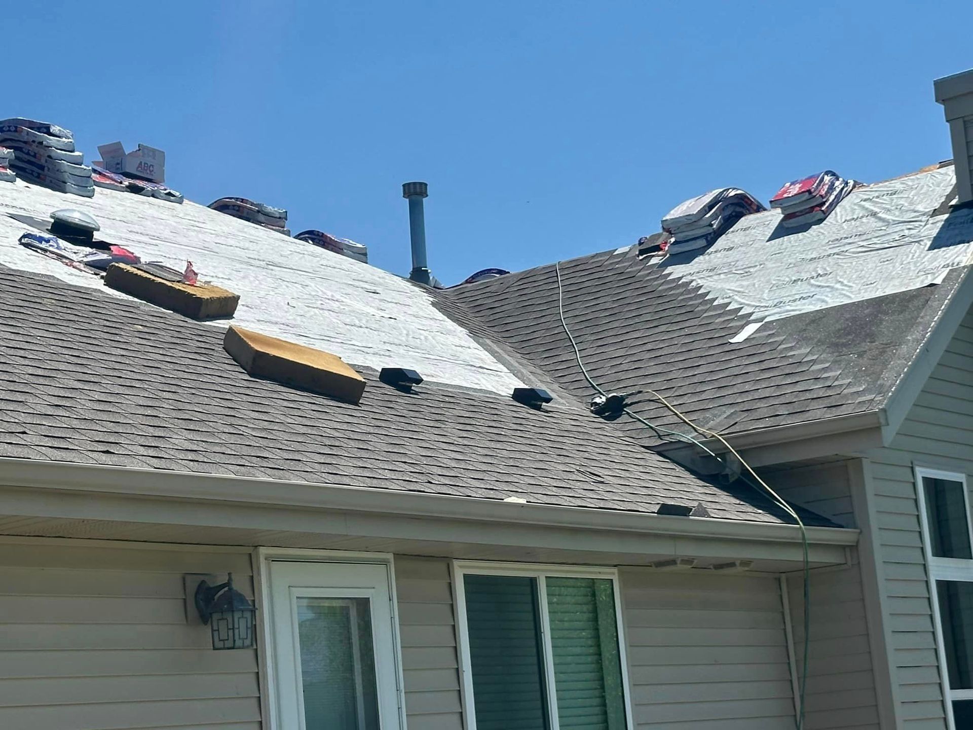 A house with a roof that is being repaired on a sunny day.