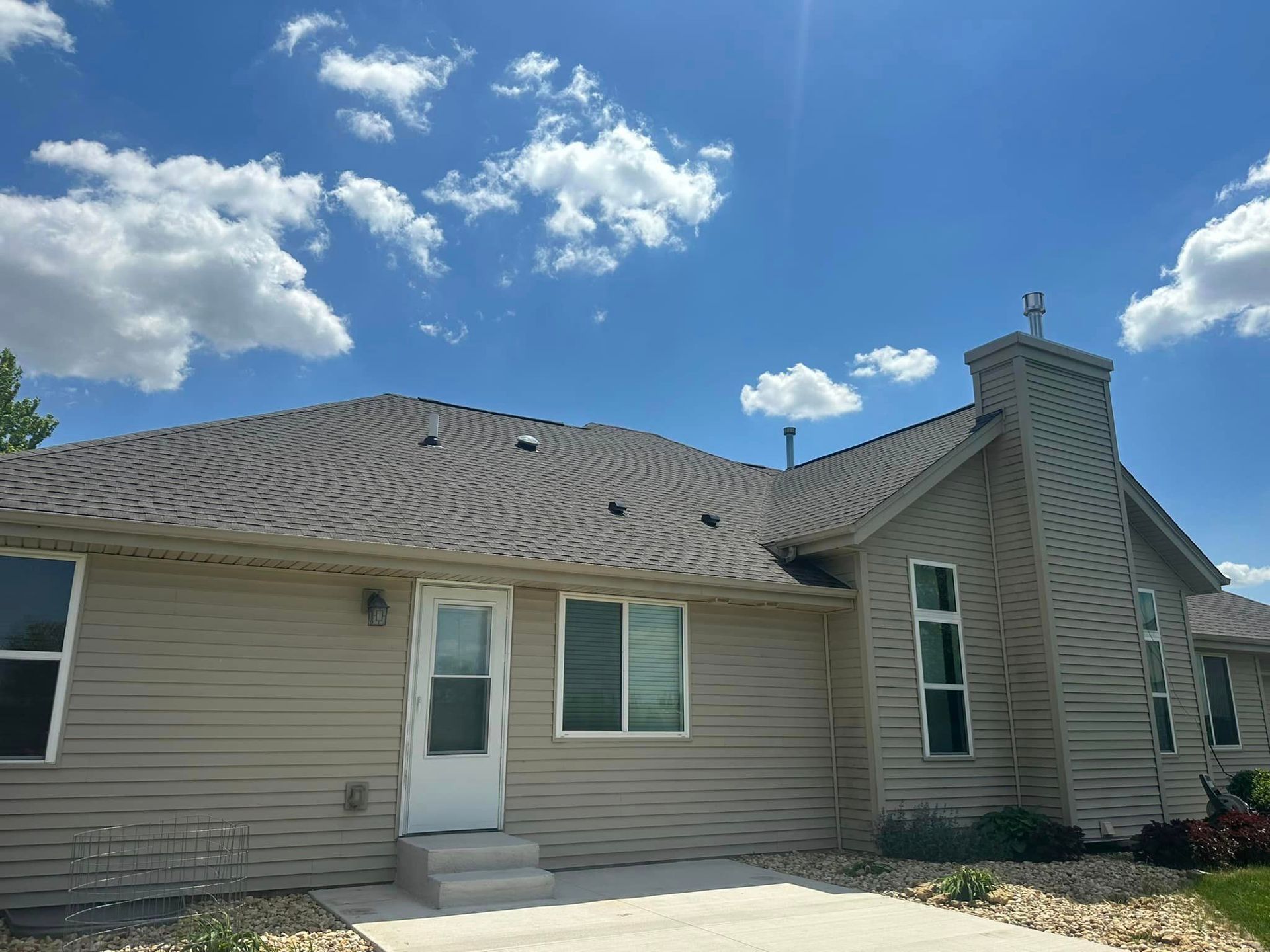 A house with a roof and a chimney on a sunny day.