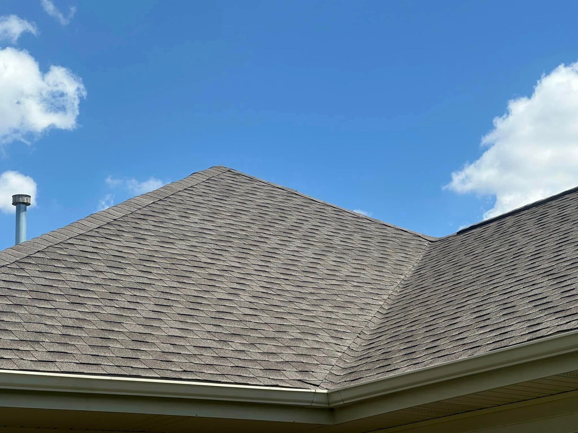 A roof with a chimney on top of it and a blue sky in the background.