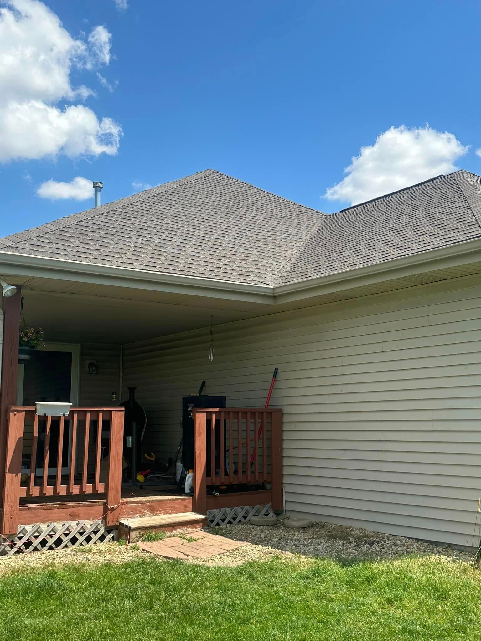 A house with a porch and a roof on a sunny day.