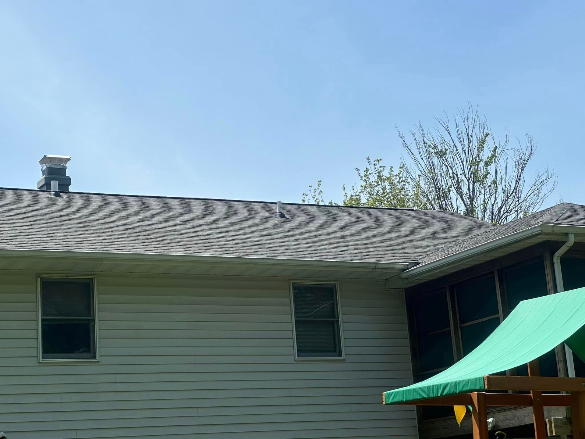 A house with a green swing set and a chimney on the roof.