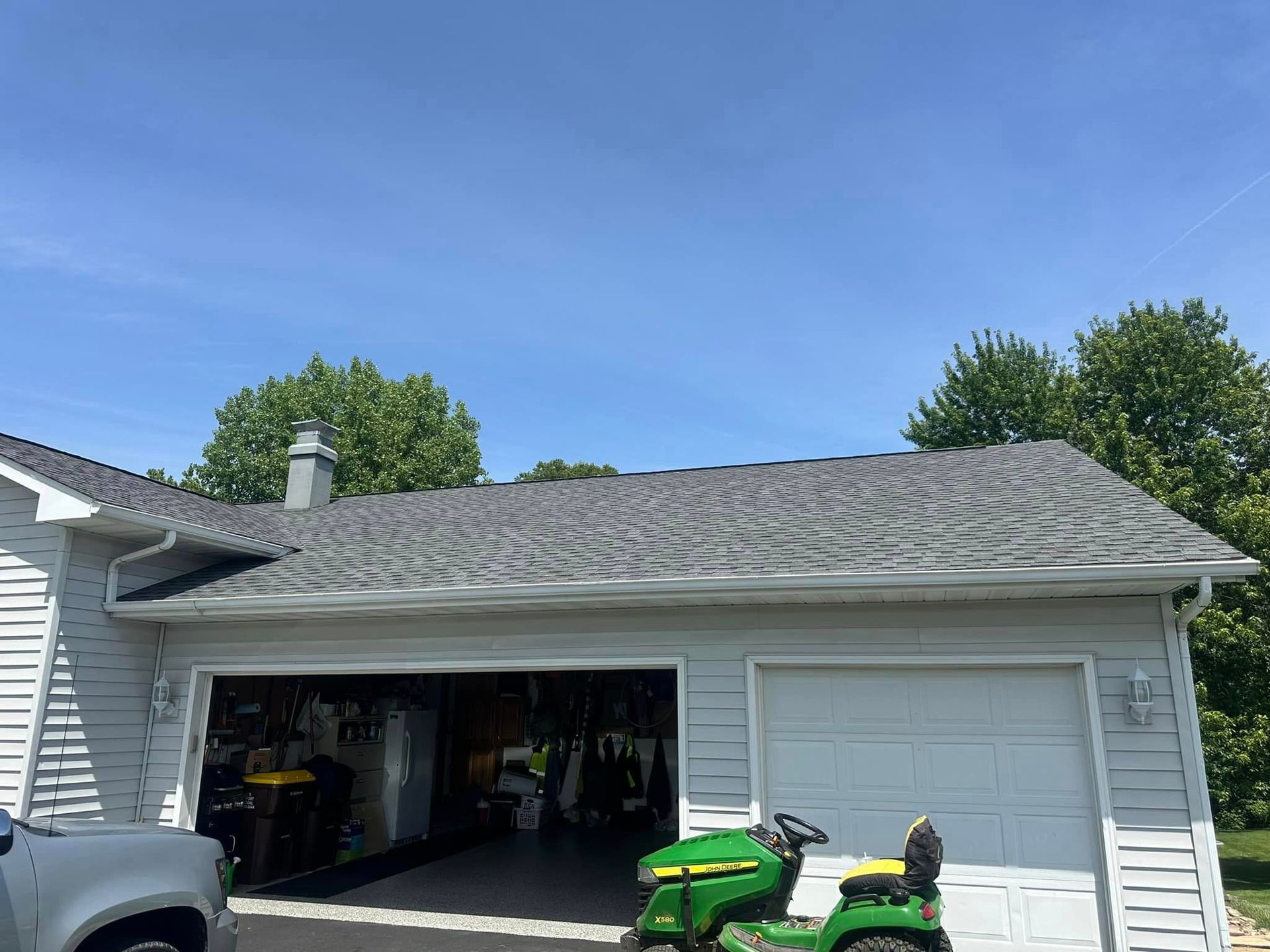 A green lawn mower is parked in the garage of a house.