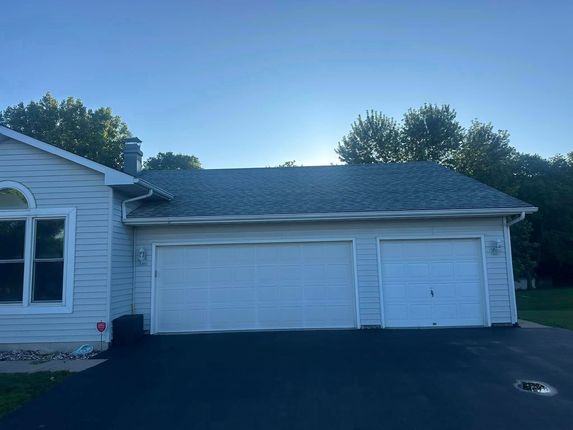 A white house with two garage doors and a blue sky in the background.