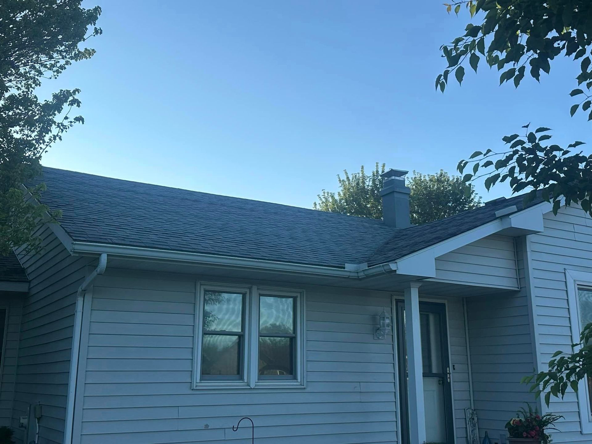 A white house with a gray roof and a chimney.