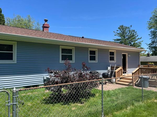 A blue house with a chain link fence in front of it.