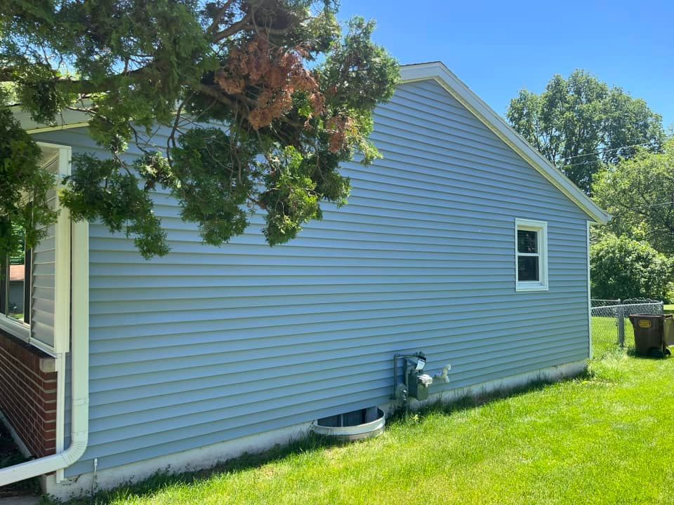 A house with a blue siding is sitting on top of a lush green lawn.