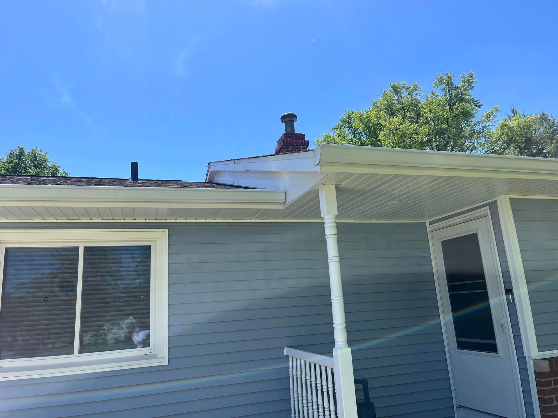A house with a porch and a chimney on the roof.