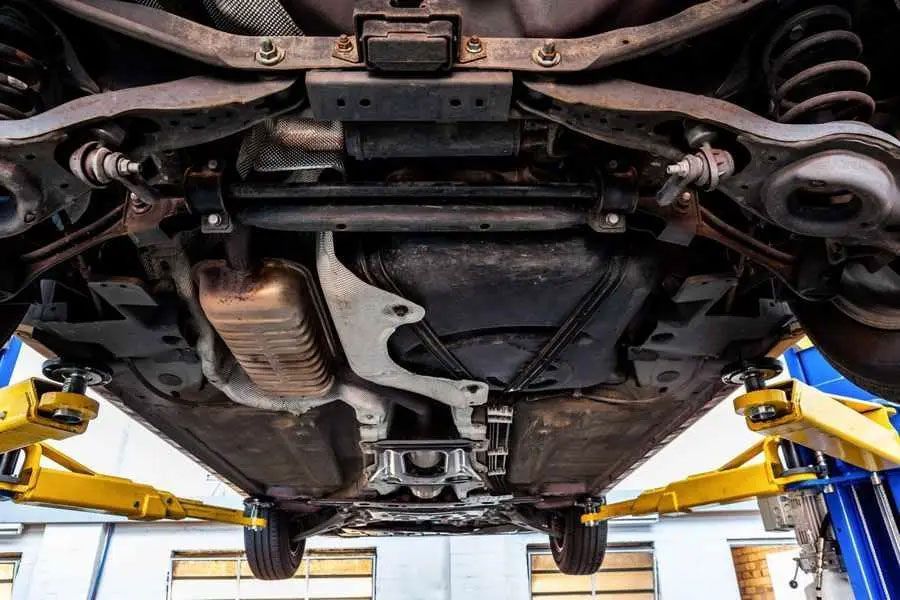 Undercarriage of a car lifted on a hydraulic lift in an auto repair shop