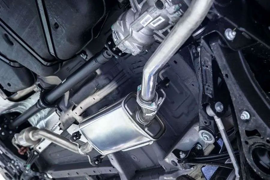 Car exhaust undercarriage with a silver muffler and pipes beneath a vehicle