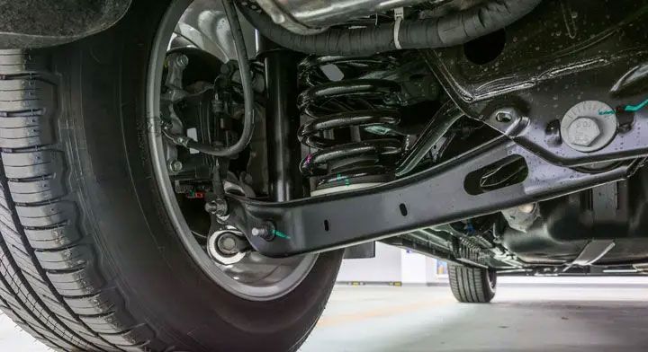 Close-up of a car’s front suspension and tire underneath the chassis.