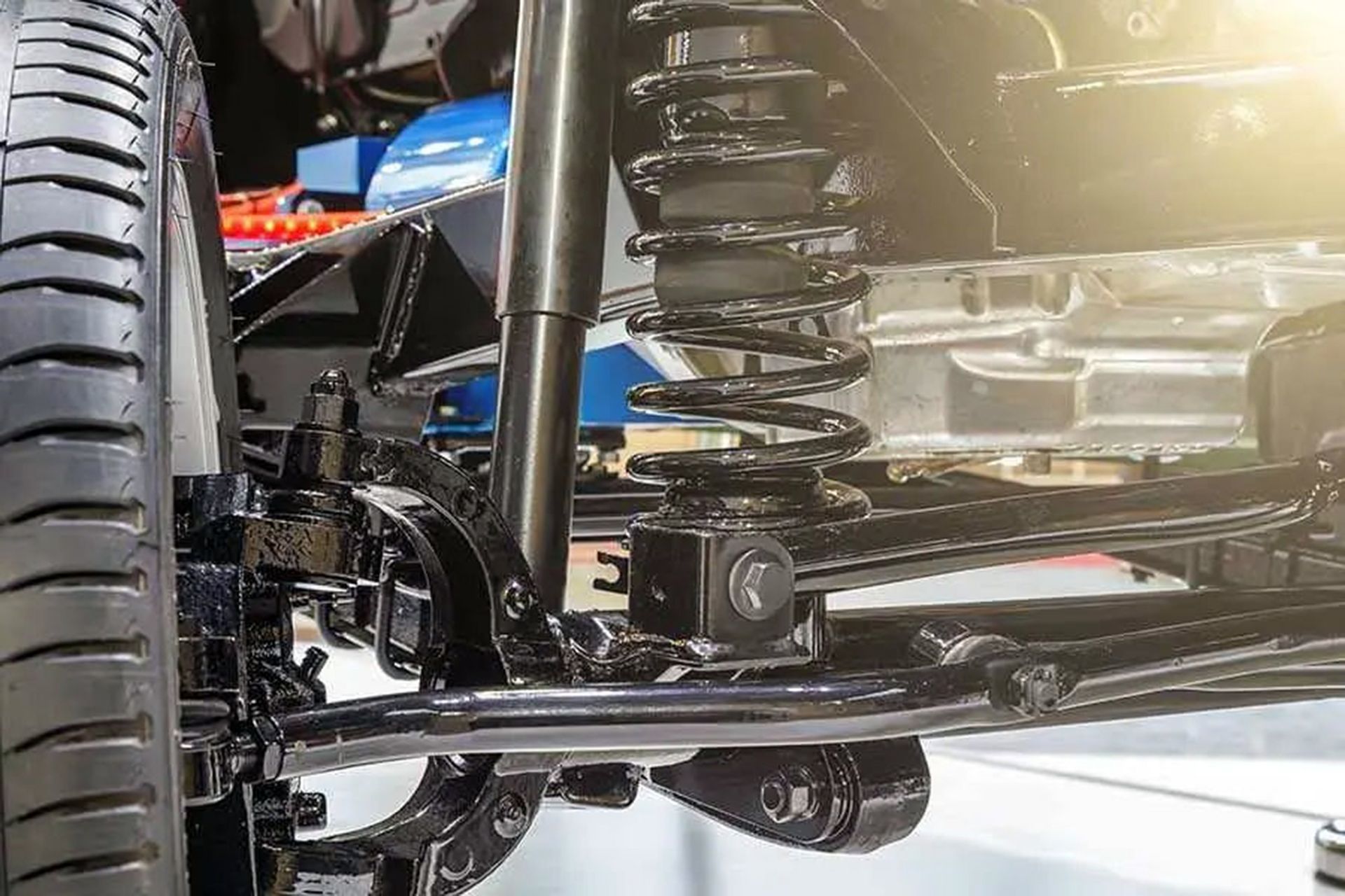 Close-up of a car’s rear suspension and tire with glossy black components and chrome details