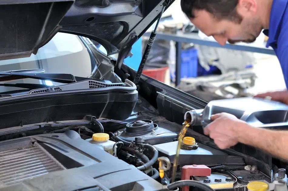 Mechanic inspecting a car engine under the hood in a garage