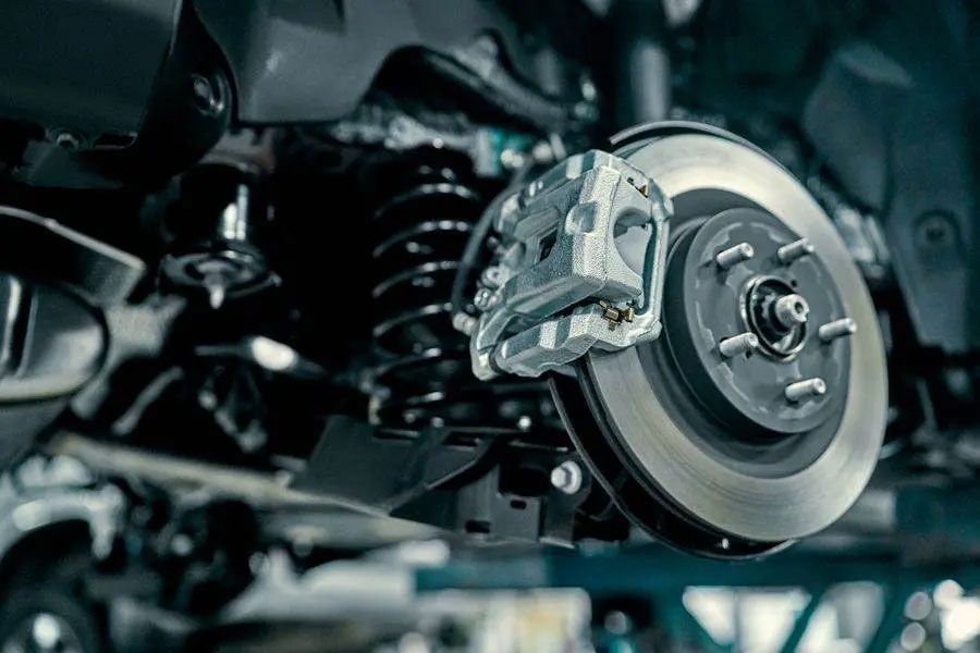 Close-up of a car wheel brake assembly and suspension in a workshop