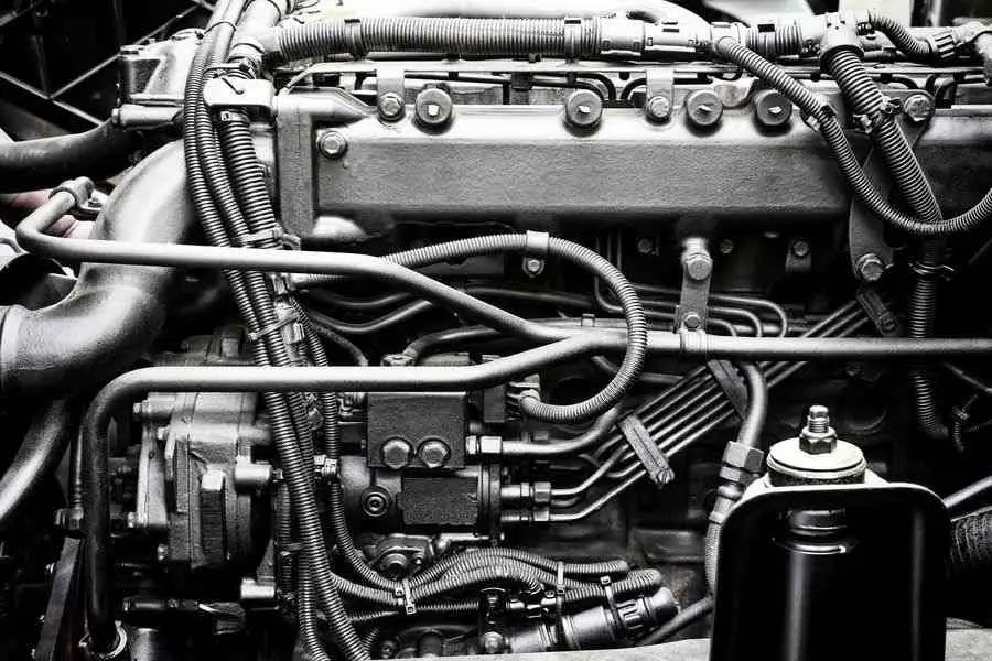 Black-and-white close-up of an engine bay with hoses, wiring, and mechanical components