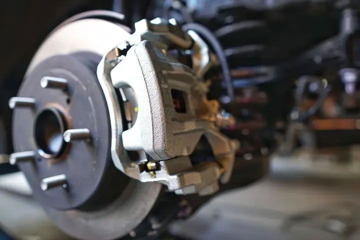 Close-up of a car brake rotor and caliper assembly in a garage.