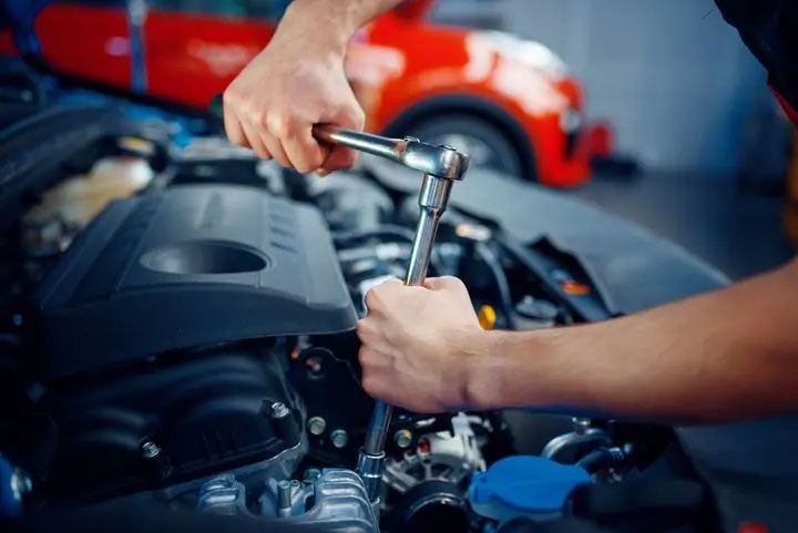 Mechanic tightening a car engine bolt with a ratchet in a garage