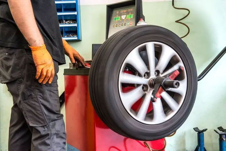 Mechanic balancing a car wheel on a tire balancing machine in a workshop