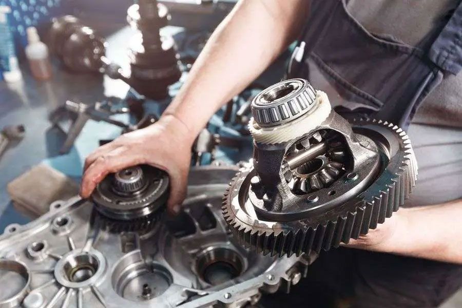 Mechanic handling gearbox gears and bearings on a workbench in a garage