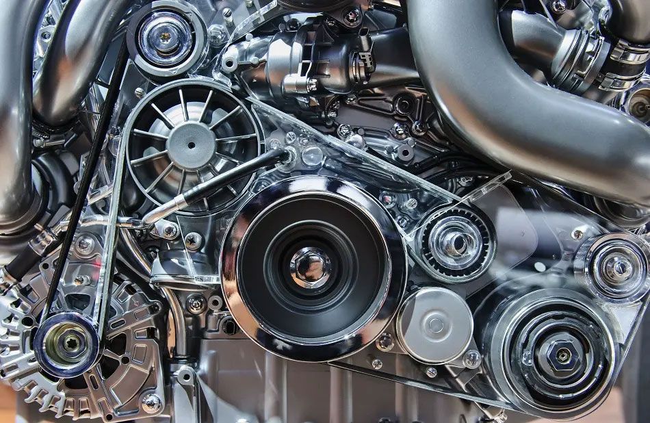 Close-up of shiny metallic engine components with belts, pulleys, and silver tubing.