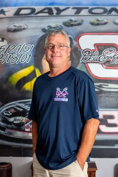 Man standing in a navy T-shirt in front of a Dayton race car mural.