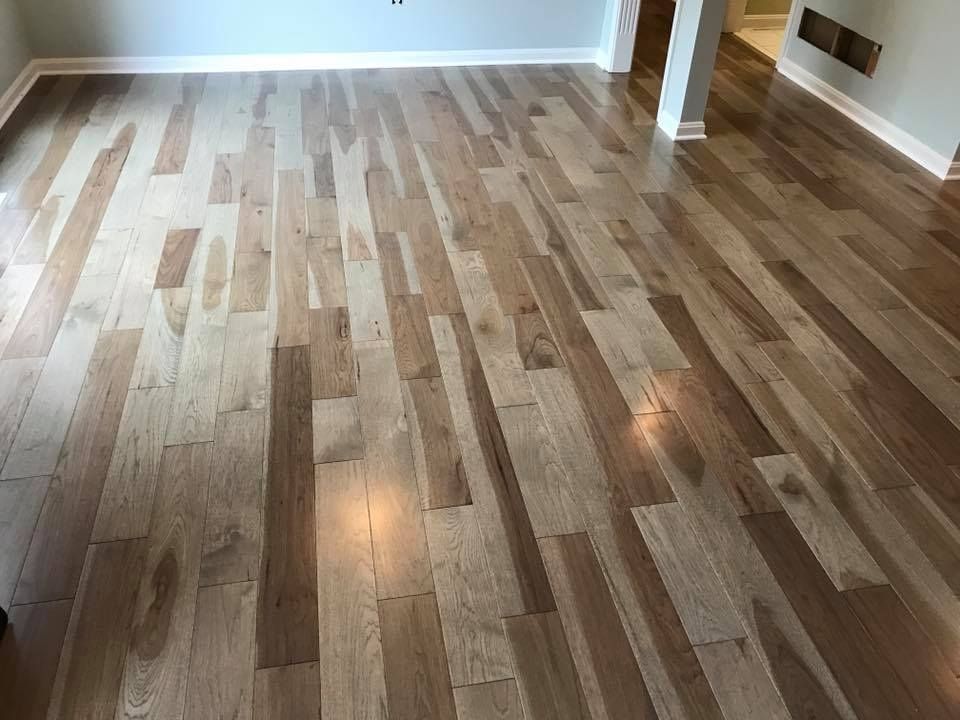 A room featuring polished hardwood flooring with varying tones of light and dark brown planks arranged in a linear pattern.