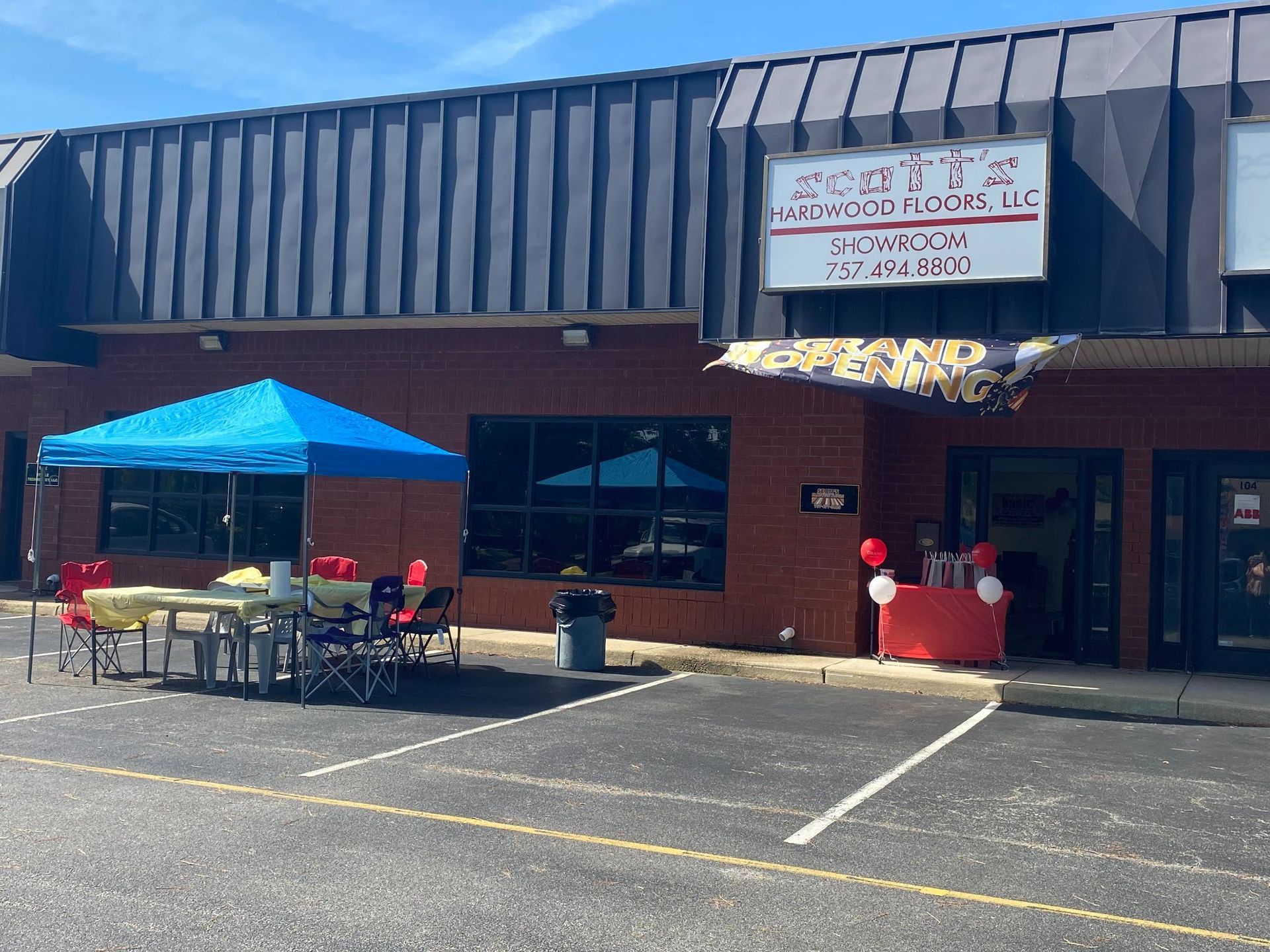 Brick storefront with blue canopy, outdoor tables, and a sign above the entrance.