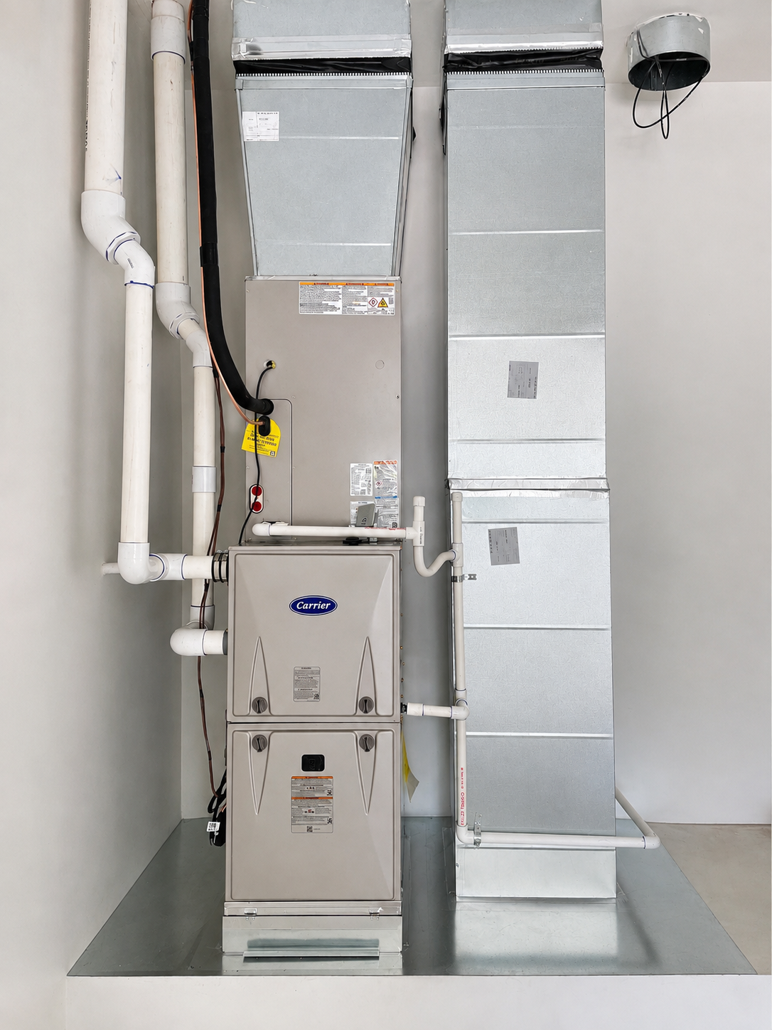 Basement utility room with furnace, ductwork, pipes, and electrical panels.