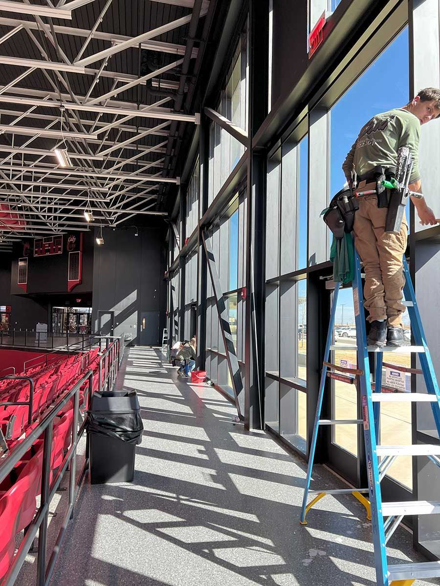 A man is standing on a ladder cleaning a window.