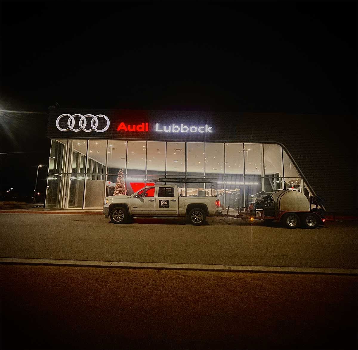 A white truck is parked in front of an audi lubbock store