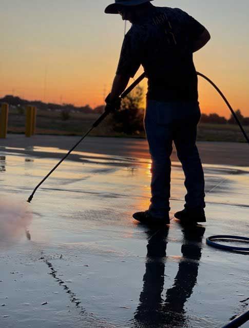 A man is using a high pressure washer to clean a concrete surface