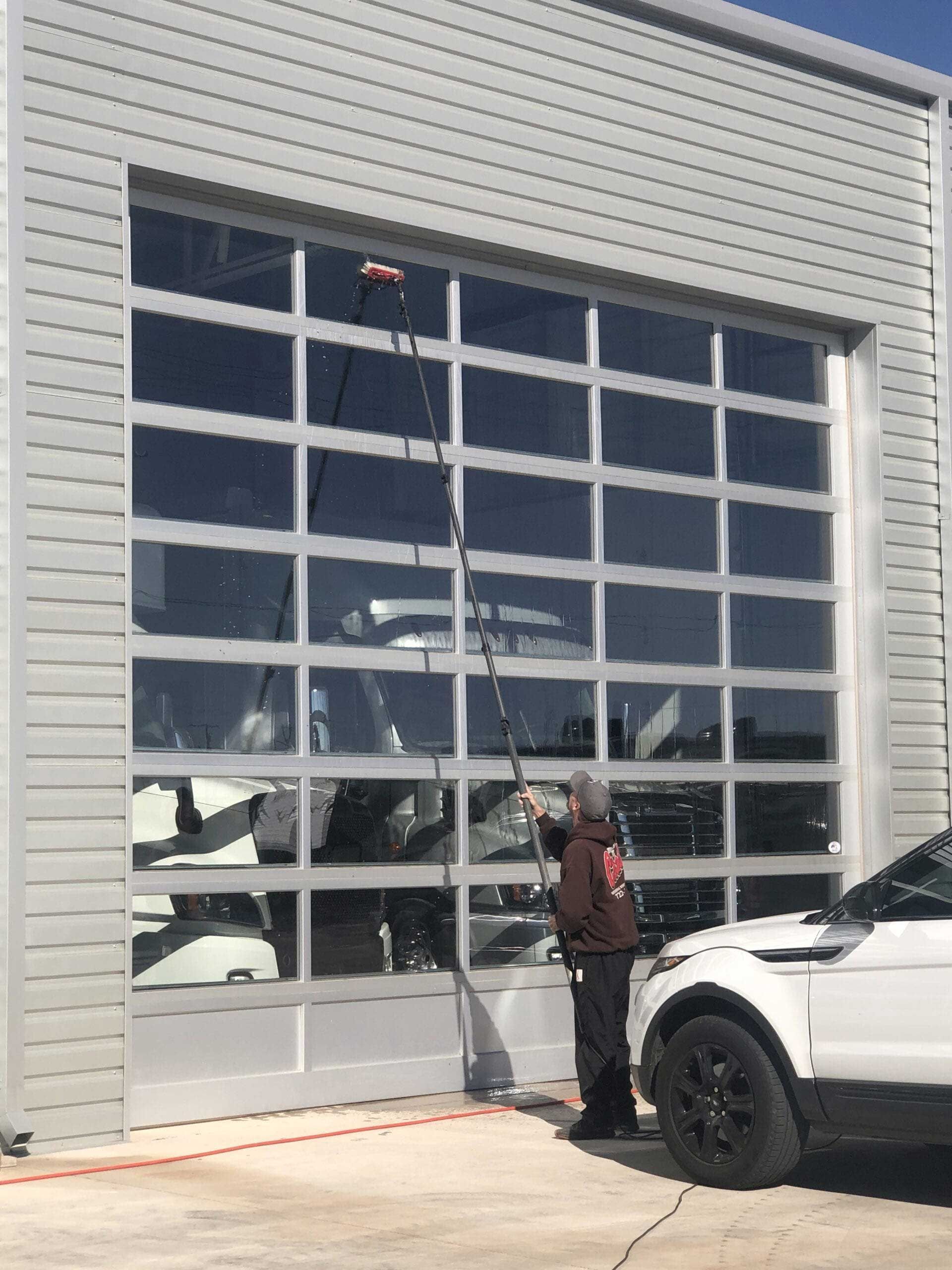 A man is cleaning the windows of a garage door.
